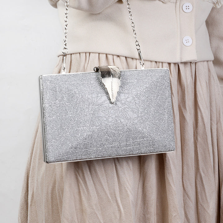 Bolso plateado de lujo con broche de hoja